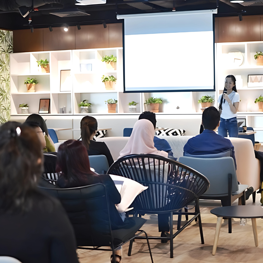 Therine Goh presenting a behavioural change workshop to employees in a modern workspace