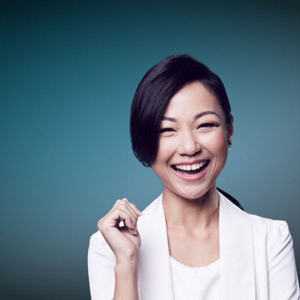 Therine Goh, corporate trainer, in a white blazer smiling confidently against a teal gradient background.